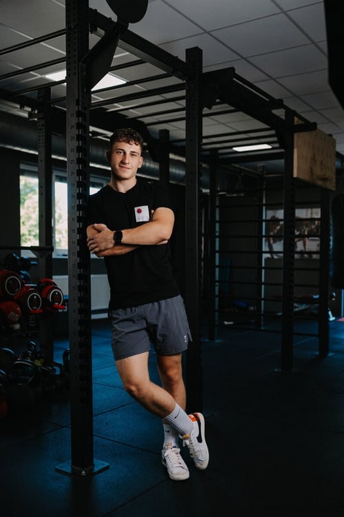Fitnesscoach Lino Schramm steht in einem Trainingsraum an einer Kraftrahmenkonstruktion.