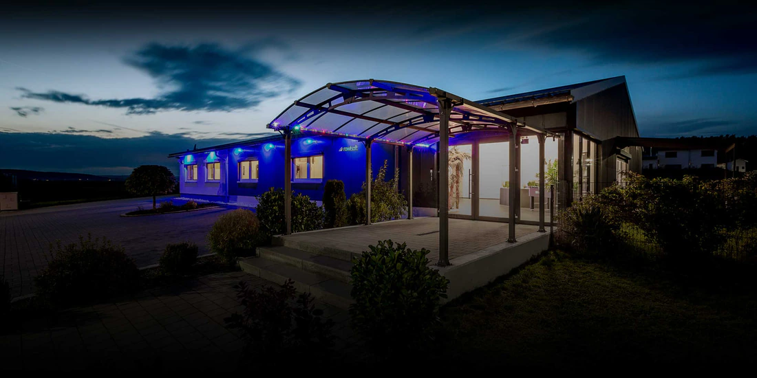 Office building exterior at dusk with blue accent lighting and a covered entrance
